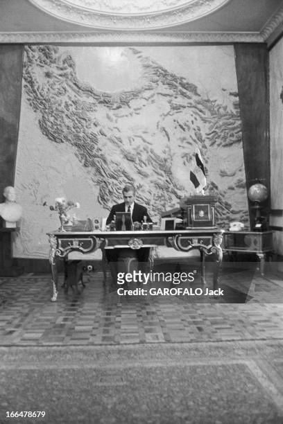 The Shah Of Iran. Téhéran- 22 Mars 1958- Le Shah Mohammad Reza PAHLAVI assis à son bureau, une carte en relief de l'Iran sur le mur du fond.