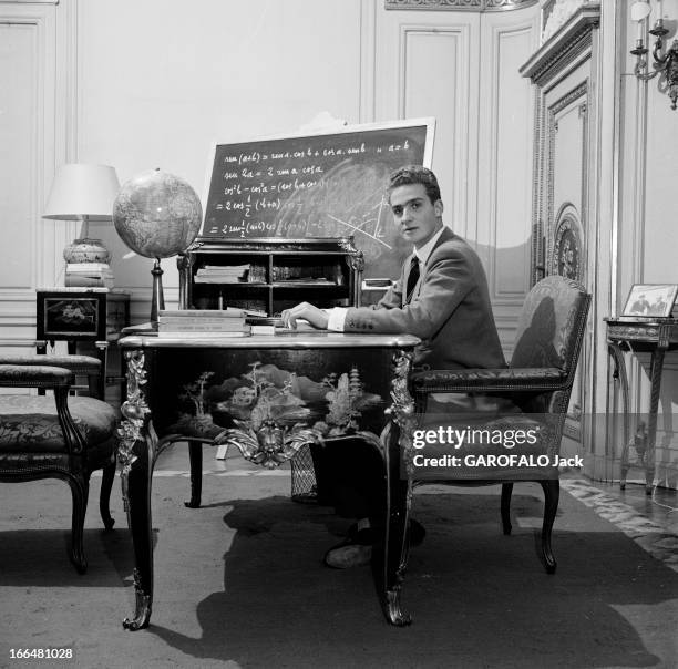 Don Juan Carlos Ist Of Spain. Espagne- période 1955-1958- Juan CARLOS IER D'ESPAGNE, en costume, assis à son bureau, un globe terrestre et des livres...