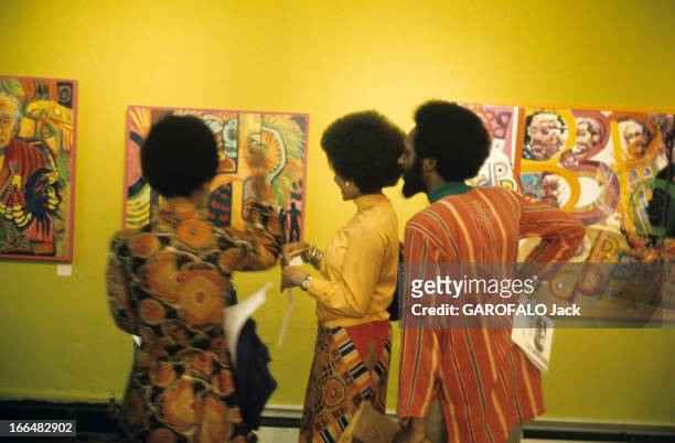 The Ghetto. New York City- Harlemle ghetto; trois afro-américains devant les toiles de FALAYEMI, défendeur du 'Black Art', lors du vernissage de son...