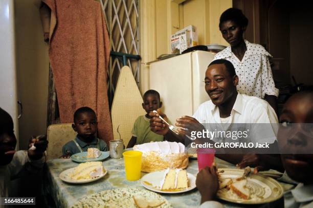 The Ghetto. New York City- Harlemle ghetto; Billy privilégié , souriant à table avec sa famille, sa femme dans leur deux pièces d'un immeuble délabré...