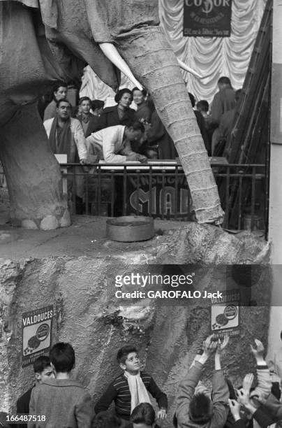 6Th Childhood Fair 1953. Paris, novembre 1953, le 6ème Salon de l'Enfance 1953 au Grand Palais. Sur un stand, un éléphant en carton distribue, avec...