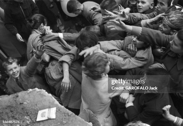 6Th Childhood Fair 1953. Paris, novembre 1953, le 6ème Salon de l'Enfance 1953 au Grand Palais. Devant un stand, un attroupement d'enfants, les bras...