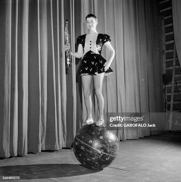 Annie Fratellini. Paris- 12 Janvier 1957- Annie FRATELLINI en costume de scène, une robe courte à manches bouffantes, un saxophone en main, debout en...