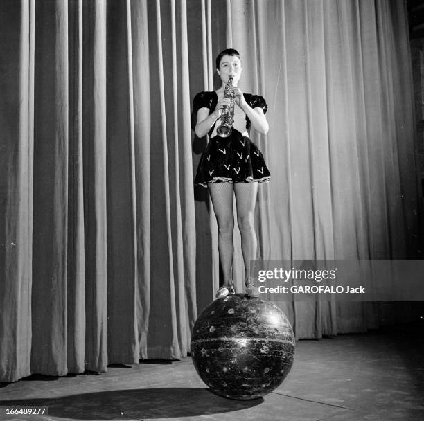 Annie Fratellini. Paris- 12 Janvier 1957- Annie FRATELLINI en costume de scène, une robe courte à manches bouffantes, jouant du saxophone, debout en...