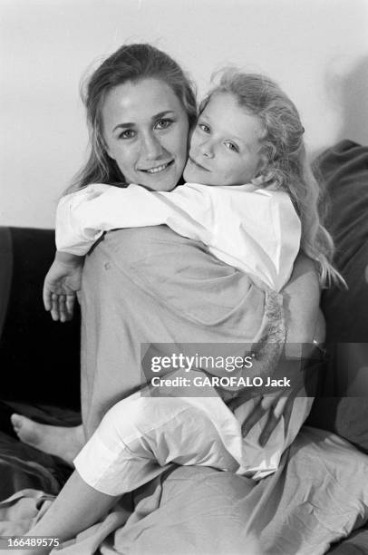 Brigitte Fossey. Paris- 5 Janvier 1977- Brigitte FOSSEY, actrice française et sa fille Marie dans ses bras sur un canapé, toutes deux souriant.