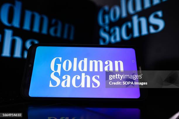 In this photo illustration a Goldman Sachs logo is displayed on a smartphone and in the background.