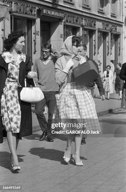 Women Fashion. Juin 1959, Paris 'les affreuses', photos de passantes sur les Champs Elysées : Une femme en robe à fleurs portant son sac sur le...