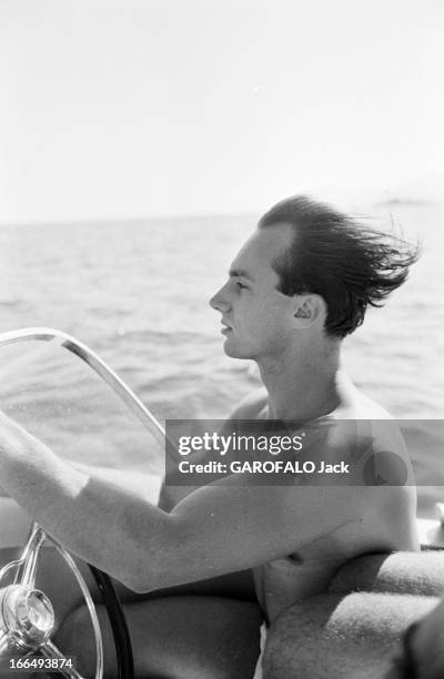 Karim Aga Khan On Holiday On The French Rivieira. Aout 1959, sur la côte d' Azur, portrait de KARIM AGA KHAN de profil cheveux au vent conduisant son...