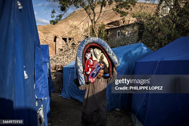 Man walks with a mattress and blankets provided for earthquake survivors in the earthquake-hit village of Ighermane near Adassil in Chichaoua...