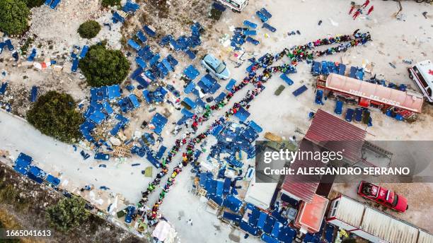 This aerial photograph taken on September 14, 2023 shows migrants gathering outside the operational center called "Hotspot" on the Italian island of...