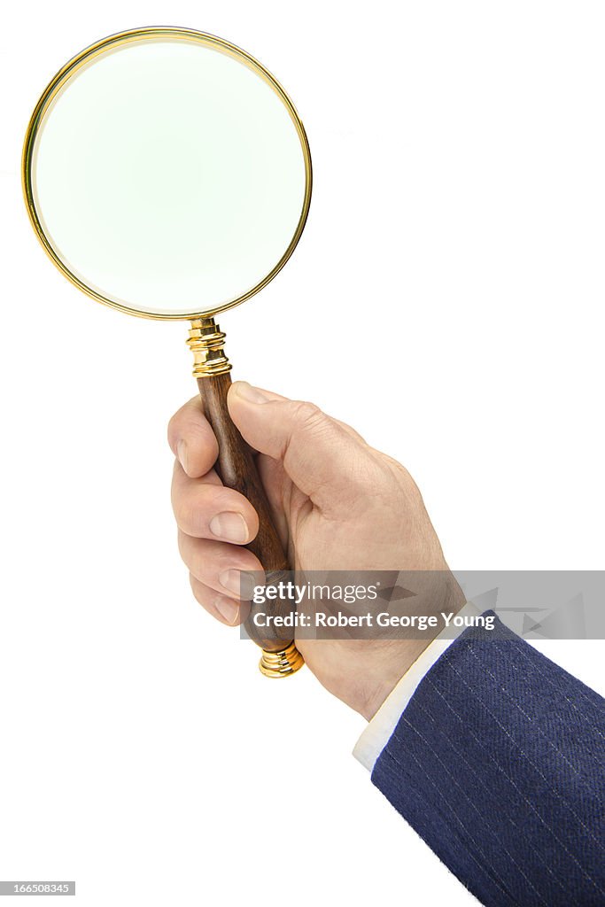 Business man holding magnifying glass