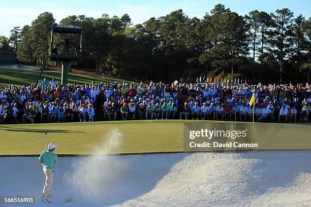 Fred Couples of the United States hits out of a bunker on the 18th hole the third round of the 2013 Masters Tournament at Augusta National Golf Club...