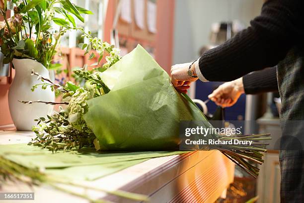 florist in her shop preparing bouquet of flowers - mazzo di fiori foto e immagini stock