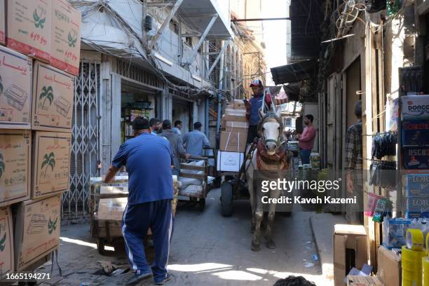 Porter talks on his mobile phone while ridding a horse ridden cart full of goods in Shorja Bazaar on March 20, 2023 in Baghdad, Iraq.