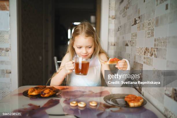 child girl with a plaster cast on her arm drinks tea at home - girl making sandwich stock pictures, royalty-free photos & images