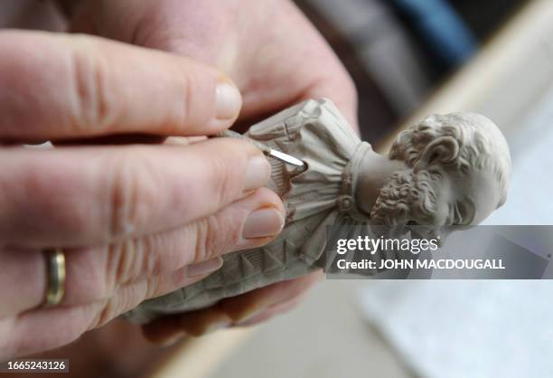 Craftswoman fine-carves a porcelain figure representing a "Laughing Harlequin" at the Meissen porcelain manufacture in Meissen January 20, 2010. The...