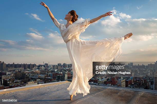 ballerina performing arabesque on roof - urban ballet stockfoto's en -beelden