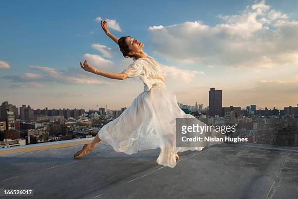ballerina performing tombé, cambré back on roof - long dress stock-fotos und bilder