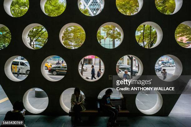 People relax in a seating area behind the facade of a building in the Gangnam district of Seoul on September 14, 2023. Seoul's Gangnam district,...