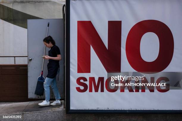 Worker walks past a huge "No Smoking" sign in the Gangnam district of Seoul on September 14, 2023. Seoul's Gangnam district, which was made famous by...