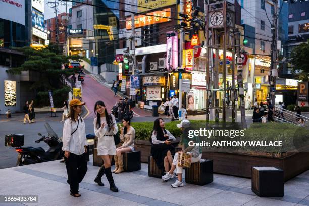 People relax in a seating area near a street in the Gangnam district of Seoul on September 14, 2023. Seoul's Gangnam district, which was made famous...
