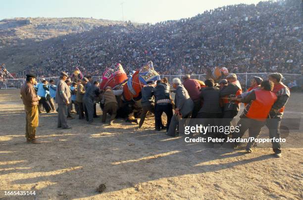 Rope men hold back two camels wrestling as a crowd of spectators watch during the annual Yoruk camel wrestling festival in a stadium beside the...