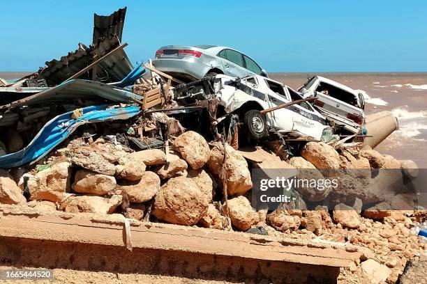 Cars are piled up atop the rubble of a building destroyed in flash floods after the Mediterranean storm "Daniel" hit Libya's eastern city of Derna,...