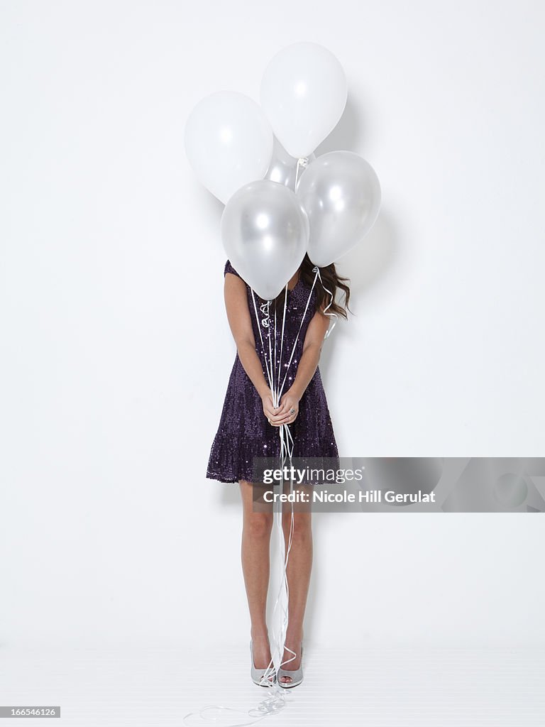 Young woman hiding behind balloons at party