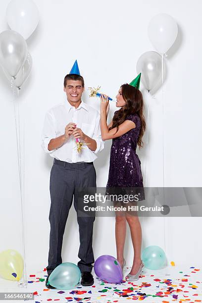 young couple blowing horns at party - part horn blower stock pictures, royalty-free photos & images