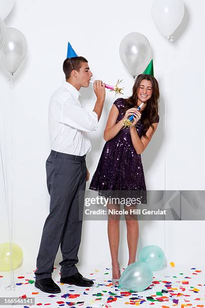 young couple blowing horns at party - part horn blower stock pictures, royalty-free photos & images