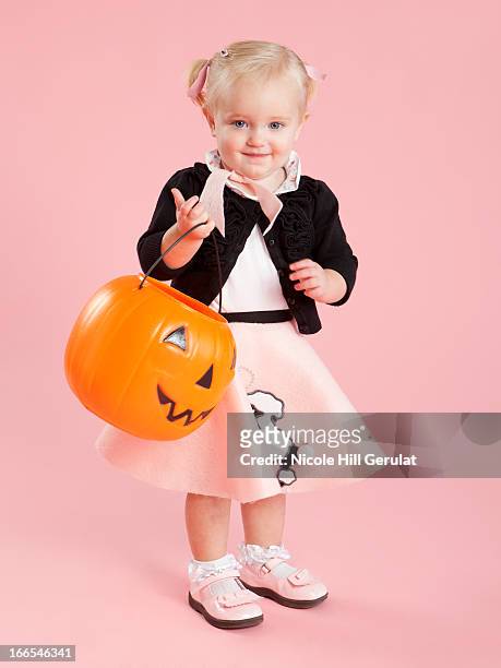 baby girl (12-17 months) in 1950s style costume, holding pumpkin lantern for halloween - poodle skirt fotografías e imágenes de stock
