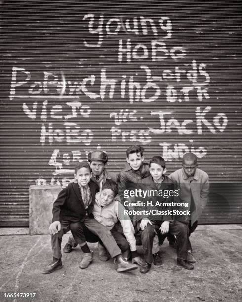 1970s Group of boys posed looking at camera under some graffiti New York city NY USA.