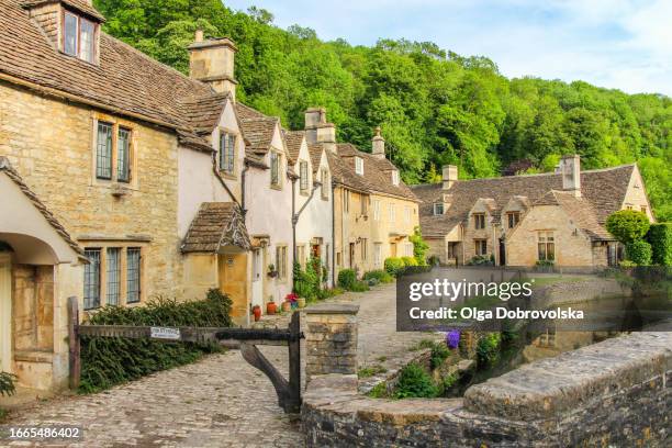 a picturesque view of the cotswold stone cottages street in castle combe - wiltshire stock pictures, royalty-free photos & images