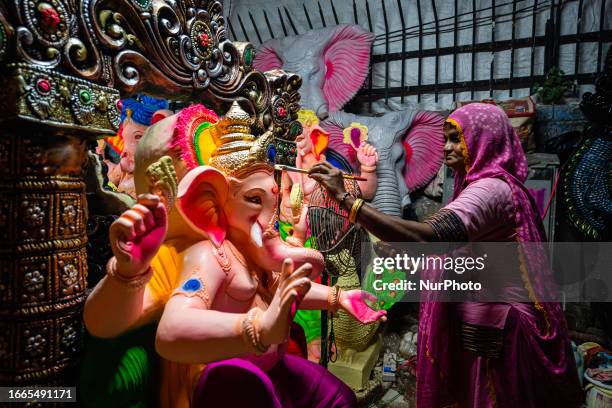 An Indian artist applies the finishing touches to a colourful clay idol of the elephant-headed Hindu God, Lord Ganesha, in Ahmedabad, in preparation...