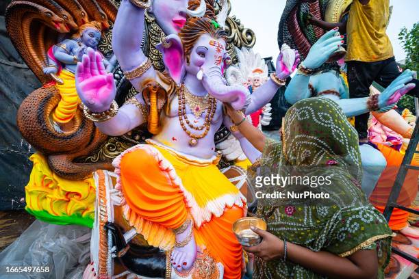 An Indian artist applies the finishing touches to a colourful clay idol of the elephant-headed Hindu God, Lord Ganesha, in Ahmedabad, in preparation...