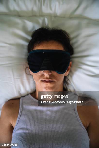 close-up of a young woman sleeping with a mask on her face. - augenmaske stock-fotos und bilder