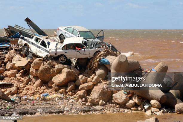 Cars are piled up atop wave breakers and the rubble of a building destroyed in flash floods after the Mediterranean storm "Daniel" hit Libya's...