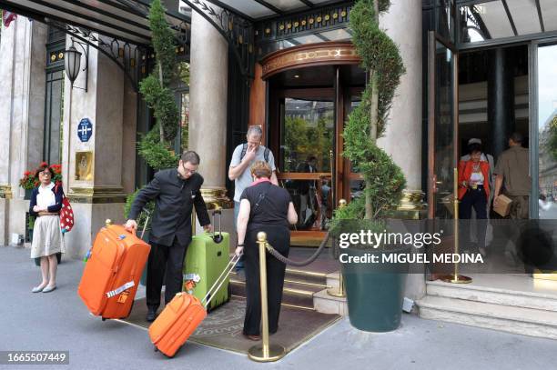 An employee carries the luggage of customers on August 12, 2010 in front of the Hotel du Louvre in Paris. AFP PHOTO / MIGUEL MEDINA