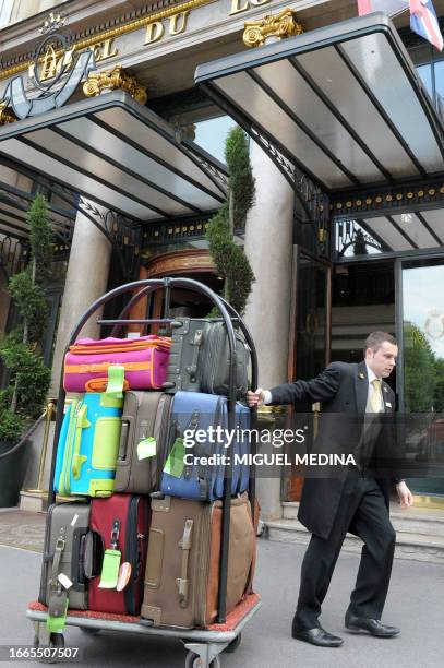 An employee pushes a trolley with customers's luggage on August 12, 2010 in front of the Hotel du Louvre in Paris. AFP PHOTO / MIGUEL MEDINA