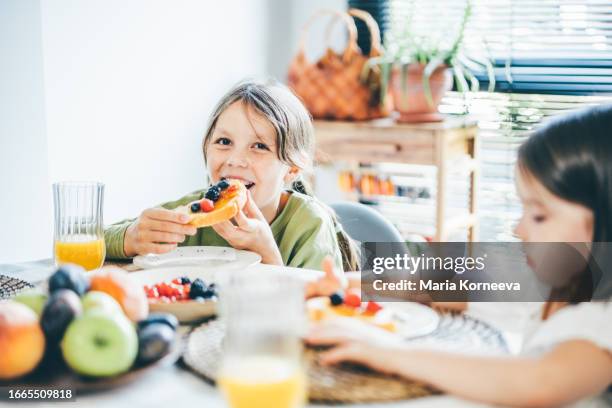 cute sisters eat a sandwich with jam and berries for breakfast. - marmalade sandwich stock pictures, royalty-free photos & images