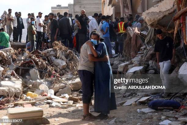 Two men comfort each other as people check the damage caused by a flash floods after the Mediterranean storm "Daniel" hit Libya's eastern city of...