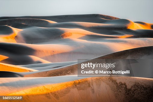 Tourist on top of massive sand dunes at sunset Tourist on top of massive sand dunes at sunset