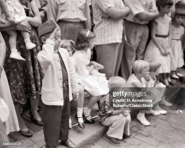 1950s Small boy wearing army cap hand up saluting at the american legion parade philadelphia pennsylvania USA.