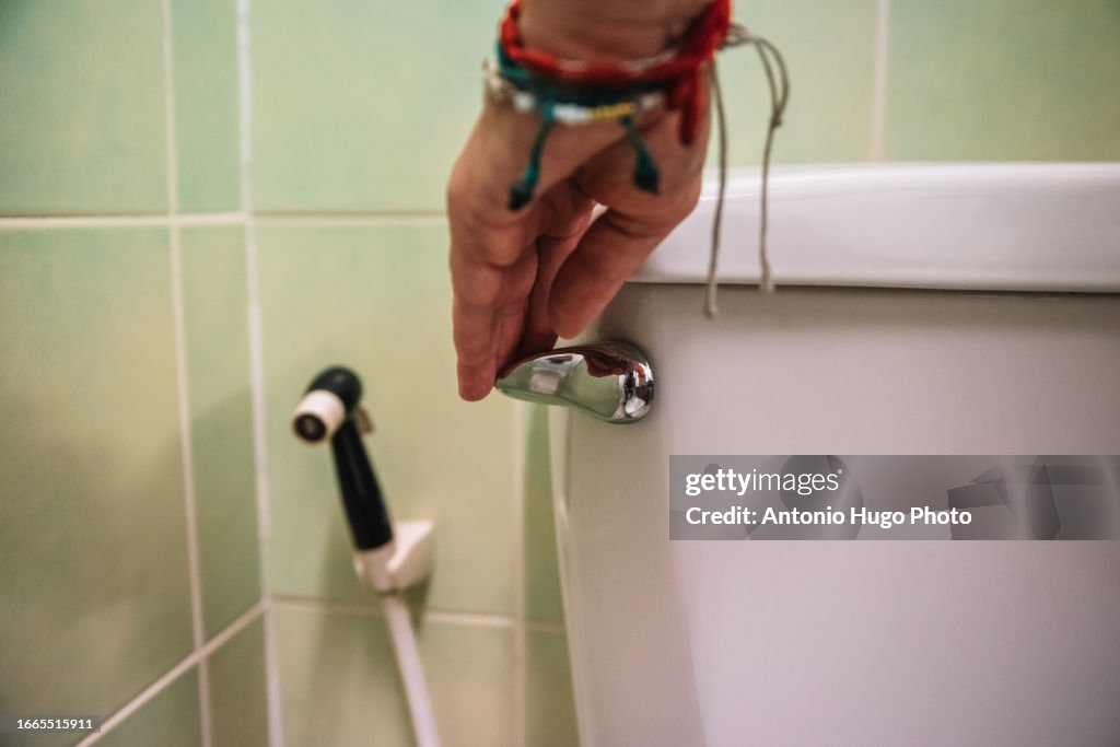 Close-up of a hand flushing a toilet
