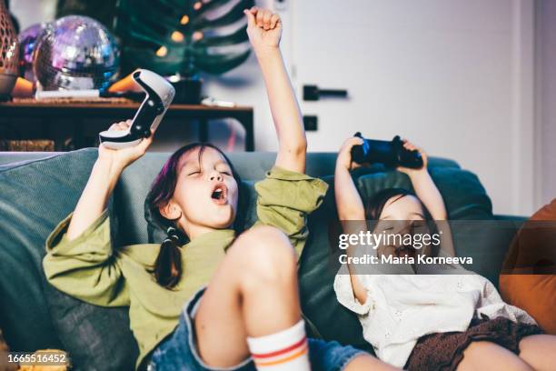 sisters playing video game at home. - marca de videojuego fotografías e imágenes de stock
