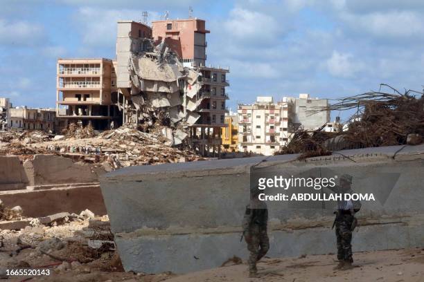 Soldiers stand in front of buildings destroyed in flash floods after the Mediterranean storm "Daniel" hit Libya's eastern city of Derna, on September...
