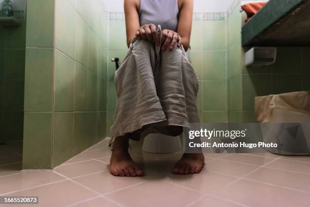 woman seated on a toilet - woman hemorrhoids fotografías e imágenes de stock