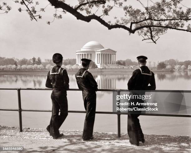 1940s Three us navy sailors in dress blues looking at jefferson memorial during cherry blossoms festival washington dc USA.