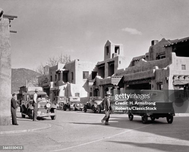 1920s Men pedestrians automobiles trucks in street in front of la fonda hotel santa fe new mexico USA.