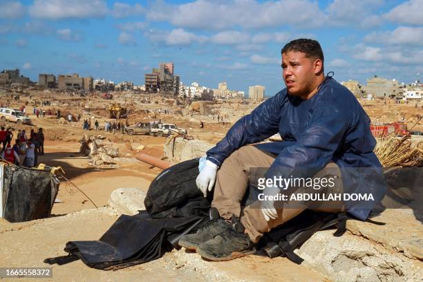 Volunteer sits on the rubble of a building in a flash flood-damaged area in Derna on September 14, 2023. A global aid effort for Libya gathered pace...